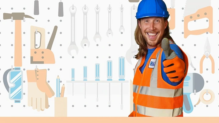 Shawn Goins smiling in a construction outfit with tools in the background as Handyman Hal.